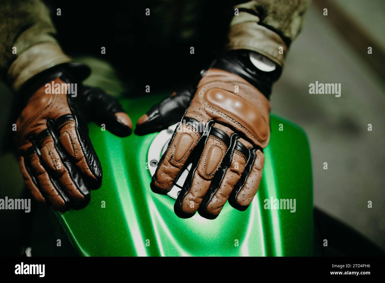 Un motociclista mostra i suoi guanti in pelle marrone per un viaggio alla macchina fotografica, l'attrezzatura Moto Foto Stock
