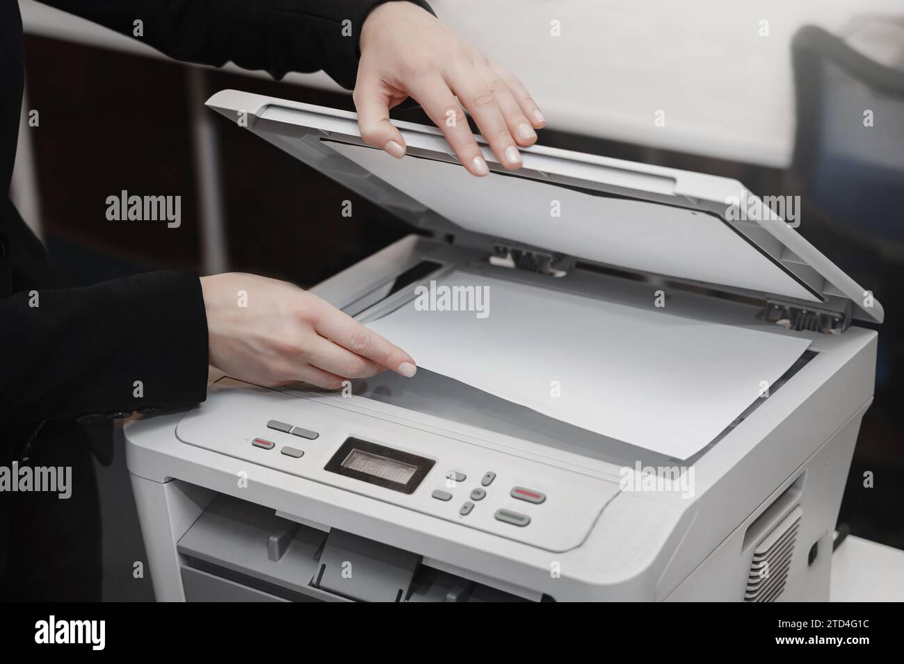 La mano di una donna in ufficio con una stampante scanner copiatrice funzionante Foto Stock