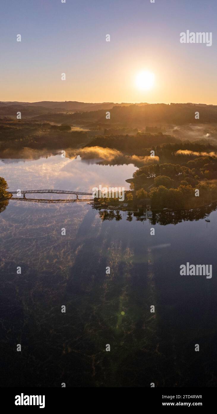 Vista aerea verticale del Lac de Saint Pardoux e del suo ponte pedonale all'alba in autunno con nebbia e specchi d'acqua Foto Stock