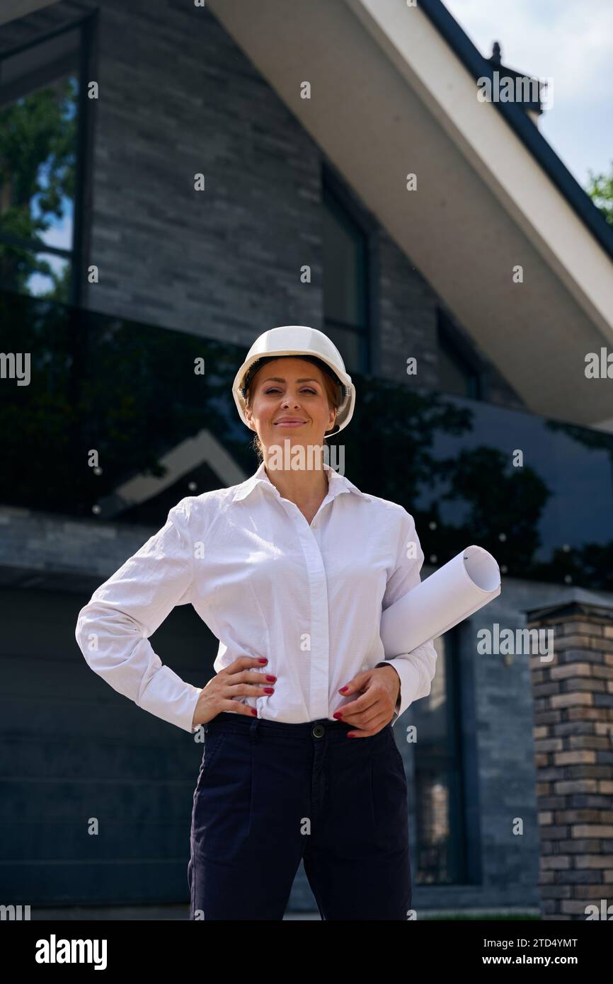 Gioiosa ispettore architettonico donna che ispeziona gli oggetti da costruzione all'aperto Foto Stock