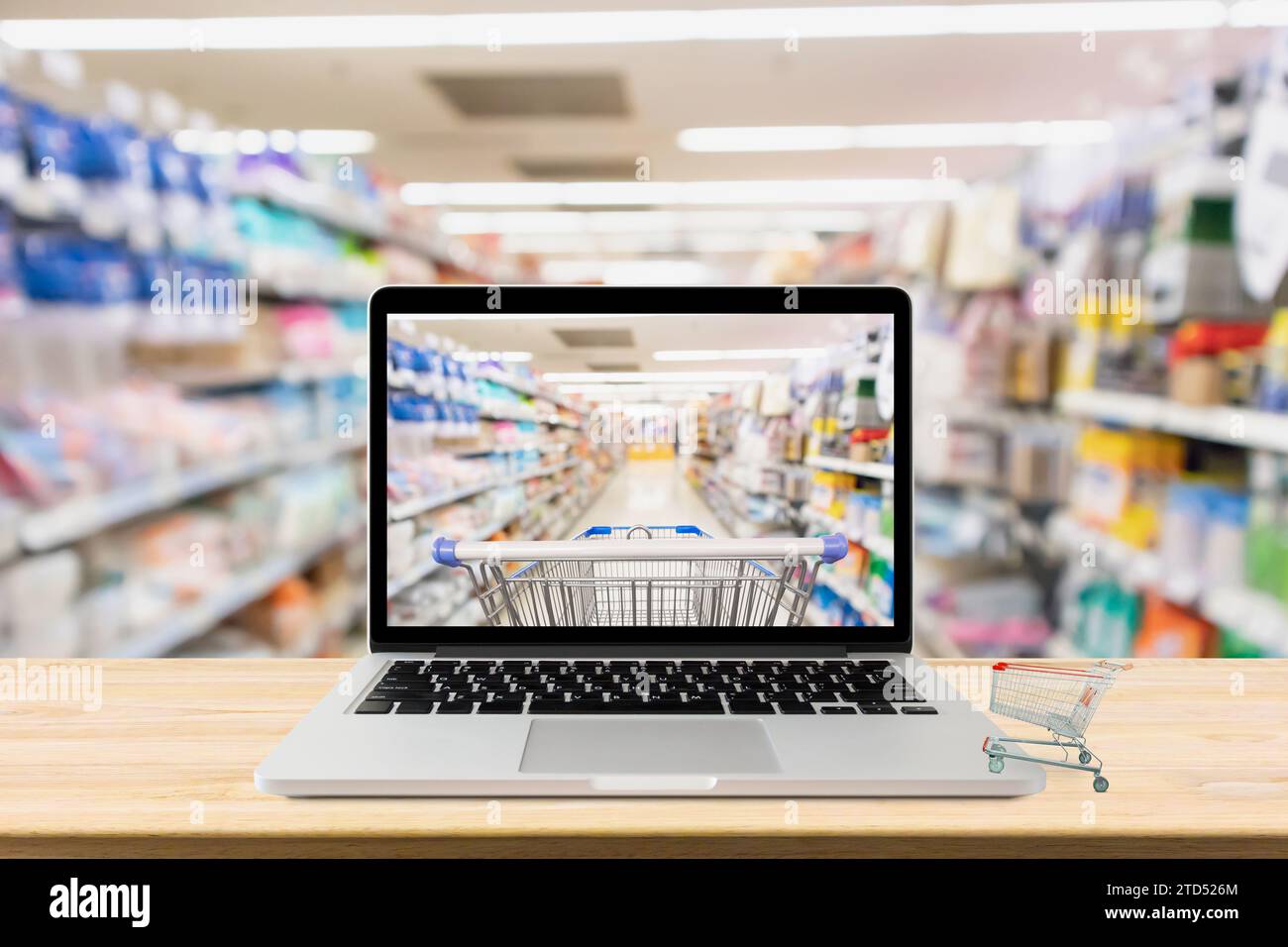 computer portatile su un tavolo di legno con concetto di shopping online sfocato nel corridoio del supermercato Foto Stock