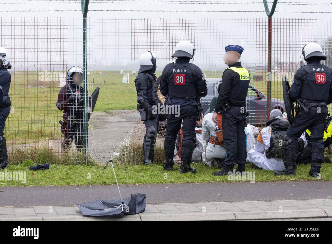 Polizia e manifestanti fotografati durante un weekend di azione di massa, organizzato dalla piattaforma d'azione per la disobbedienza civile Code Red/ Code Rood/ Code Rouge, contro il settore dell'aviazione, sabato 16 dicembre 2023, all'aeroporto di Anversa a Deurne, Anversa. Gli attivisti chiedono la fine dei sussidi per il settore, il divieto dei jet privati e una riduzione radicale dell'aviazione. BELGA FOTO NICOLAS MAETERLINCK Foto Stock