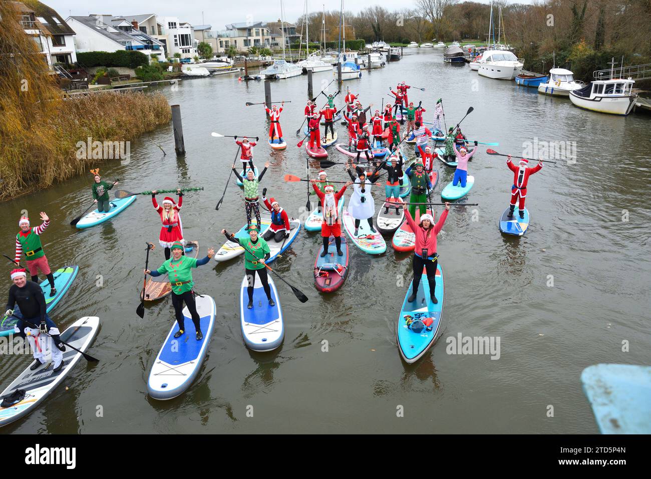 Gruppo di paddle boarder vestiti da Babbo Natale ed Elfi. Evento natalizio organizzato dai BH Activity Junkies sul fiume Stour a Christchurch Dorset Regno Unito Foto Stock