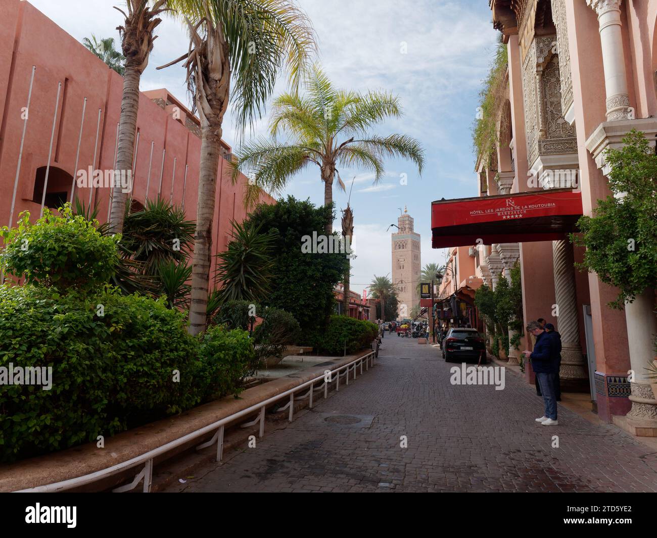 Via nella Medina di Marrakech con dietro la moschea di Koutoubia e in primo piano dell'hotel durante il giorno, Marocco, 16 dicembre 2023 Foto Stock