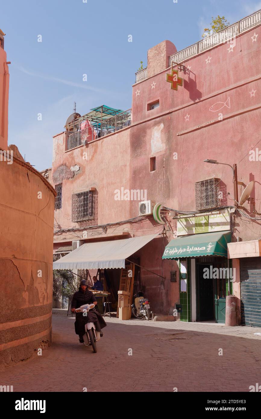 Motociclisti e negozi in una strada tradizionale nella Medina di Marrakech durante il giorno, Marocco, 16 dicembre 2023 Foto Stock