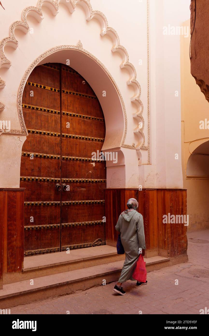 Passeggia attraverso un'elegante grande porta d'ingresso in legno in una strada nella Medina di Marrakech durante il giorno, Marocco, 16 dicembre 2023 Foto Stock