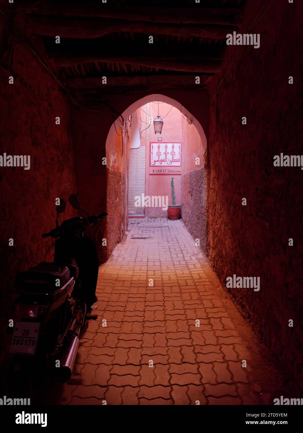 Narrow Street nella Medina di Marrakech con una moto e una luce che si riversa di fronte ad un arco, Marocco, 16 dicembre 2023 Foto Stock