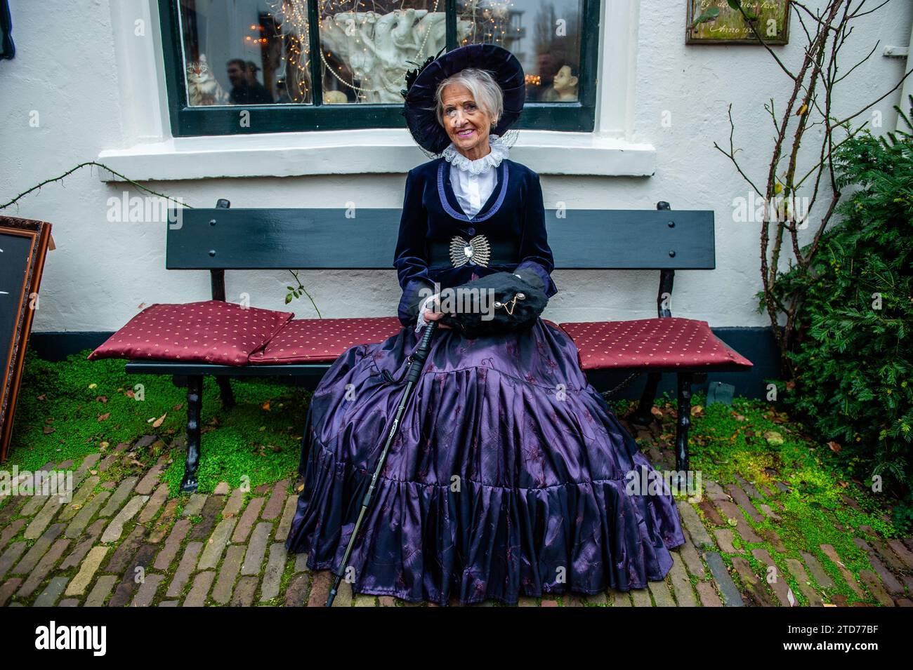 Deventer, Paesi Bassi . 16 dicembre 2023. Una donna siede su una panchina vestita con un costume vittoriano. Ogni anno, intorno a questa data, il mondo del XIX secolo dello scrittore inglese Charles Dickens rivive nella splendida città olandese di Deventer. Più di 950 personaggi dei famosi libri di Dickens Back to Life. Benestanti signore e signori con i migliori cappelli sfilano per le strade. Il paesaggio del festival è costituito da edifici storici, alberi di Natale e migliaia di piccole luci. Credito: SOPA Images Limited/Alamy Live News Foto Stock