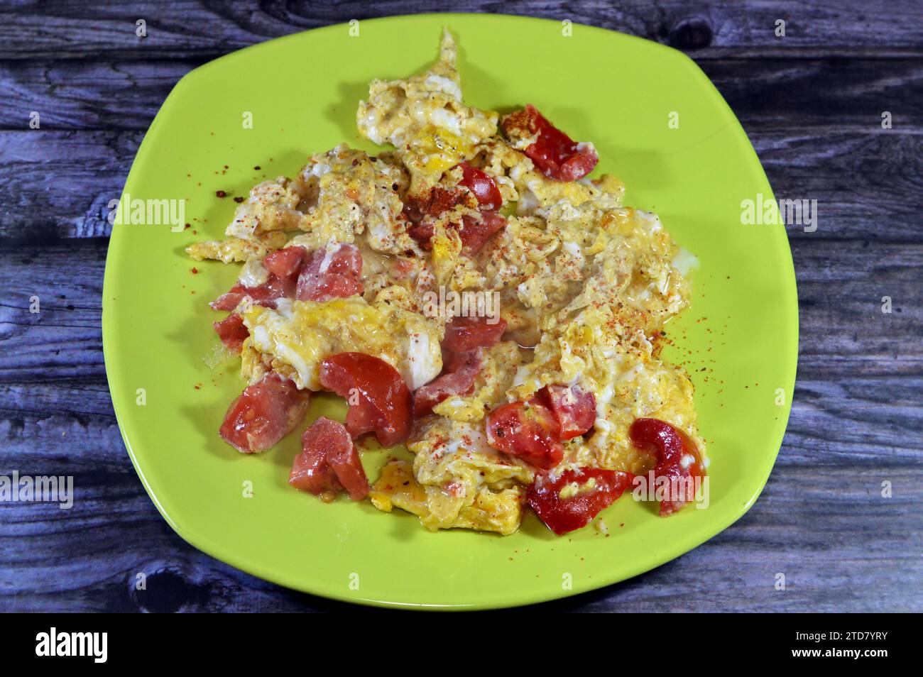 Uova strapazzate con pomodori, un piatto a base di uova mescolate, montate o sbattute insieme mentre vengono riscaldate delicatamente, con sale, burro, olio e pe nero Foto Stock