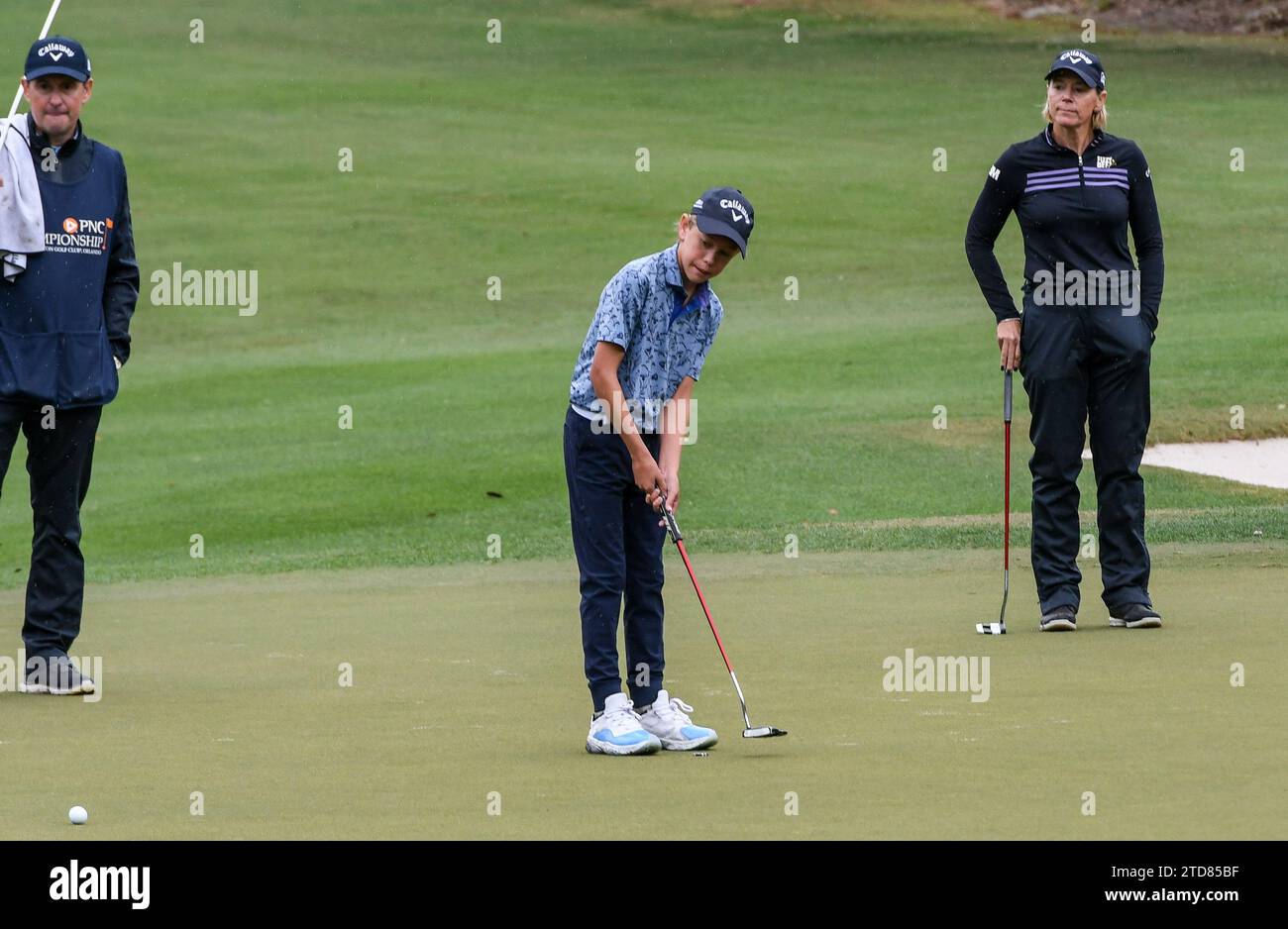 Orlando, Stati Uniti. 16 dicembre 2023. Will McGee colpisce un putt sulla nona buca mentre sua madre, Annika Sorenstam, svedese, e suo padre, Mike McGee, guardano durante il primo round del campionato PNC al Ritz-Carlton Golf Club di Orlando. Credito: SOPA Images Limited/Alamy Live News Foto Stock