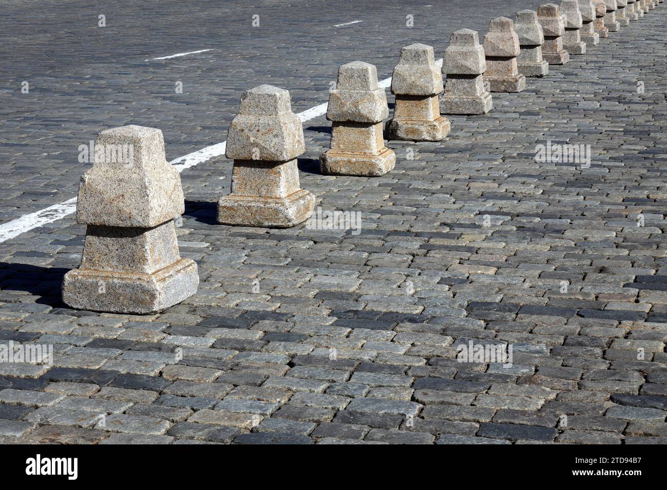 Barriera dalla lunga linea di piramidi di granito sulla vista laterale della pavimentazione stradale Foto Stock