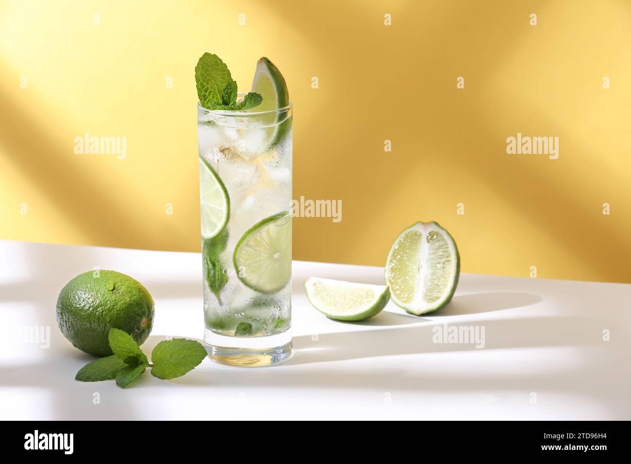 Ghiaccio e mojito in un bicchiere giacciono sul tavolo con un'ombra forte Foto Stock