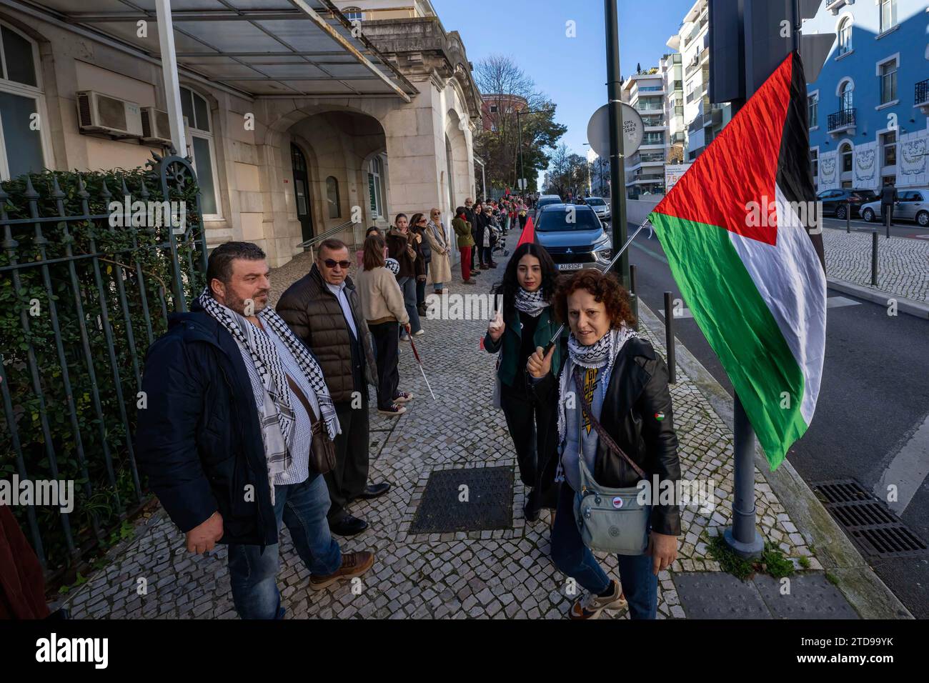 Lisbona, Portogallo. 16 dicembre 2023. Un attivista tiene una manifestazione di bandiera palestinese vicino all'ambasciata israeliana. Le azioni di protesta sono state organizzate dal PUSP - Plataforma Unitária de Solidariedade com a Palestina, il che richiede al governo israeliano un cessate il fuoco immediato e permanente, la fine dell'assedio e l'ingresso illimitato di aiuti umanitari nella Striscia di Gaza, nonché la fine dell'aggressione nelle città, nei villaggi e nei campi profughi di tutta la Palestina. Credito: SOPA Images Limited/Alamy Live News Foto Stock