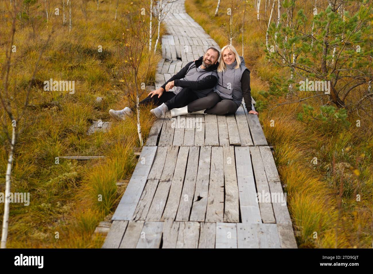 Una coppia siede su un sentiero di legno in una palude a Yelnya, Bielorussia. Foto Stock