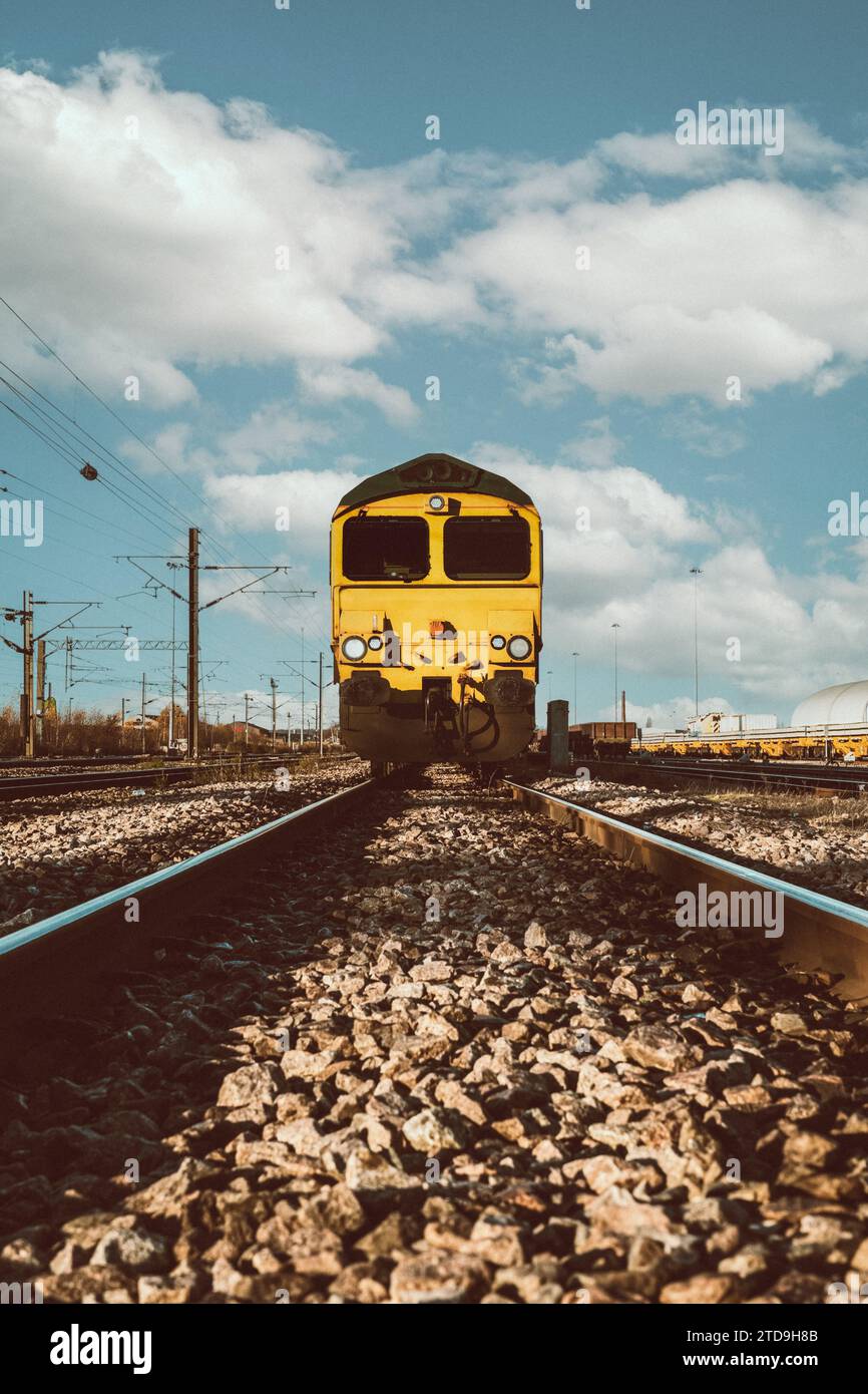 Punto di vista ad angolo ridotto di una locomotiva ferroviaria merci che si avvicina su binari ferroviari e traversine con spazio di copia Foto Stock