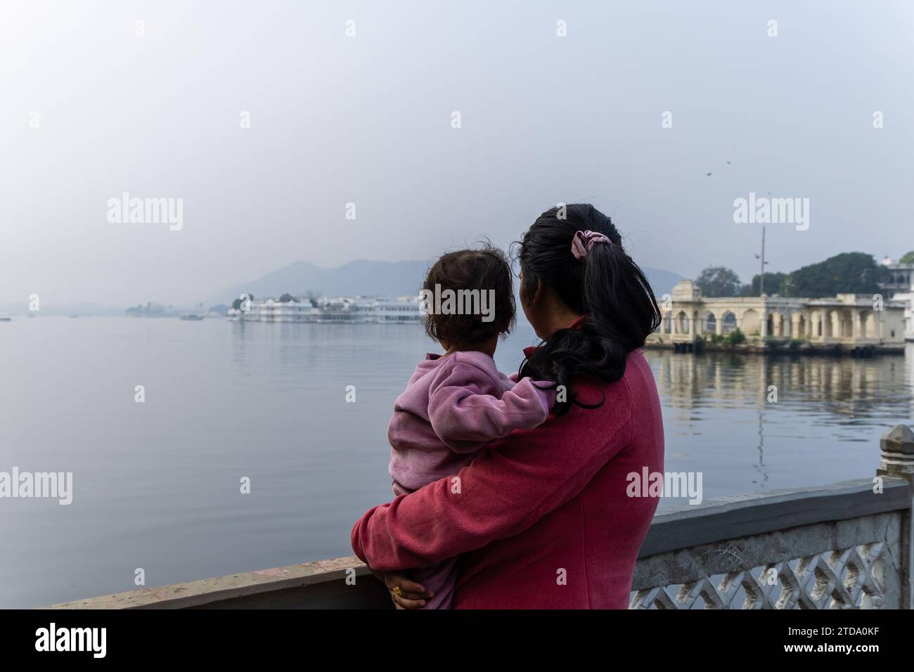 Una giovane madre con suo figlio che guarda il paesaggio di montagna della città del lago all'immagine mattutina viene scattata al Tempio Jagdish di udaipur nel rajasthan in india. Foto Stock