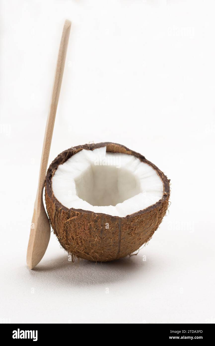 Mezzo cocco fresco con cucchiaio di legno. Sfondo bianco. Primo piano Foto Stock