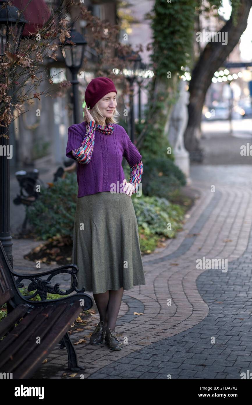 Una donna sta vicino a una panchina in strada. Foto Stock