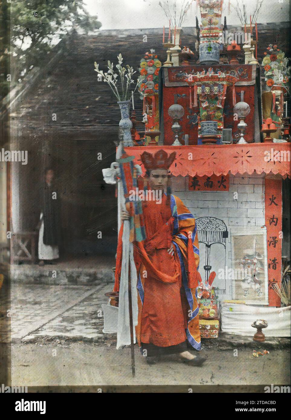 Tonkin, Indocina il Thay-phu-thuy di fronte all'edificio che simboleggia la prigione infernale con porte sorvegliate da immagini di demoni, religione, abbigliamento, arte, esseri umani, buddismo, abbigliamento religioso, pratica religiosa, Scultura, altare, accessorio, banner, banner, prigione, acconciatura, copricapo, decorazione scolpita, uomo, Indocina, Tonchino, Tonkin, 01/01/1921 - 31/12/1921, Busy, Léon, Léon fotografo Busy en Indochine, Autochrome, Photo, Glass, Autochrome, foto, positivo, verticale Foto Stock