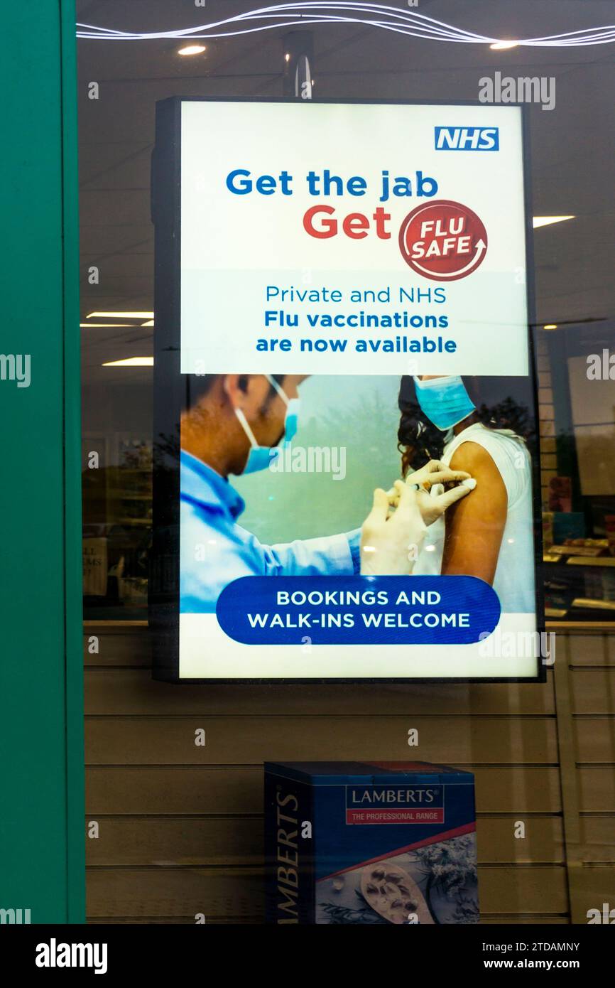 Un cartello NHS in una finestra della farmacia incoraggia le persone ad avere un jab influenzale. Foto Stock
