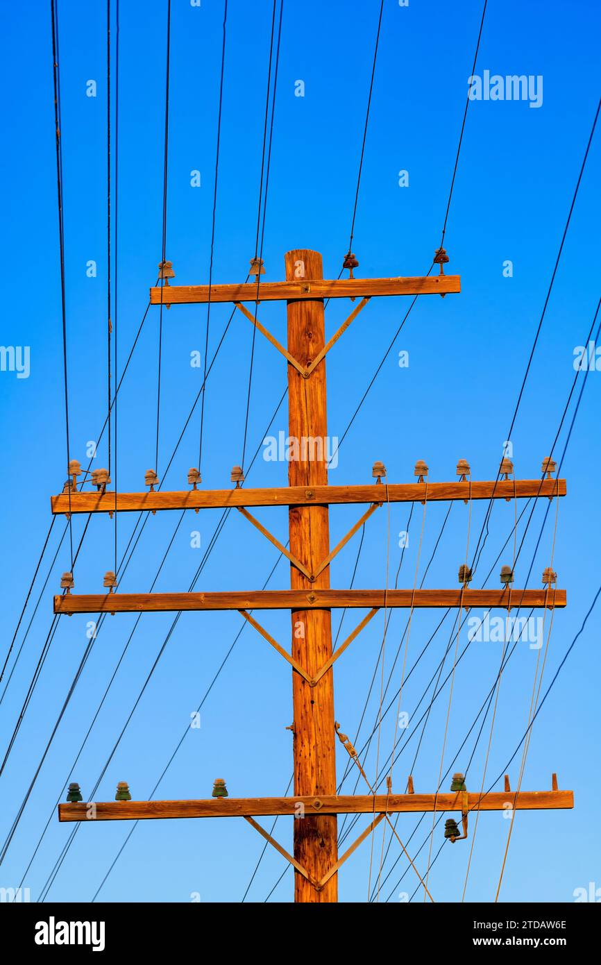Vecchio palo telefonico in legno con linee elettriche Foto Stock