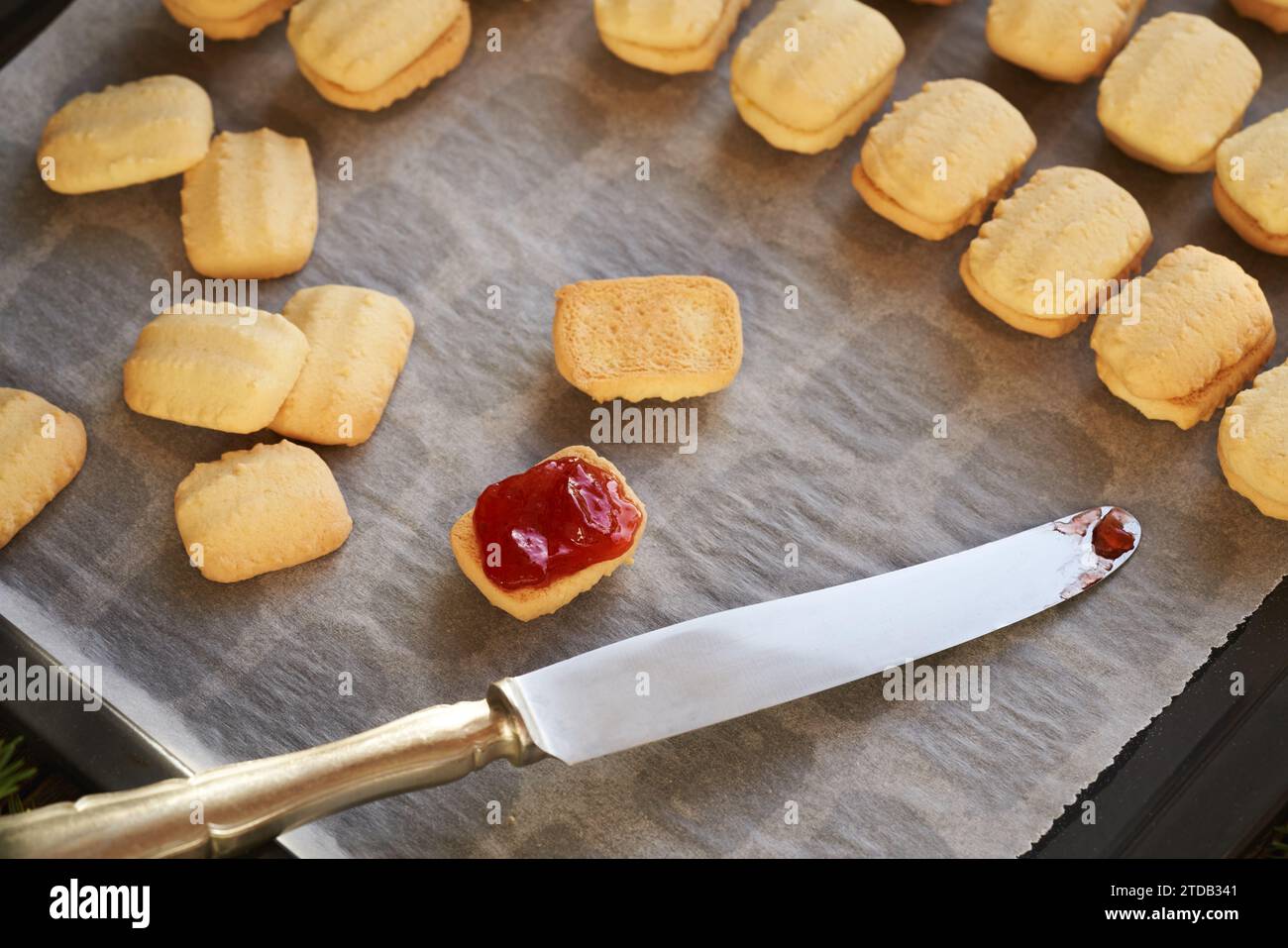 Spalmare marmellata di fragole rosse su biscotti natalizi fatti in casa Foto Stock