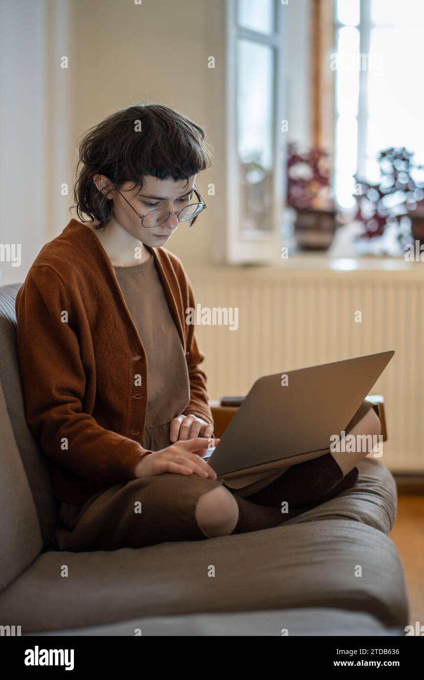 Adolescente pensiva che passa del tempo a casa, usa il laptop, lavora come freelance, studia online Foto Stock