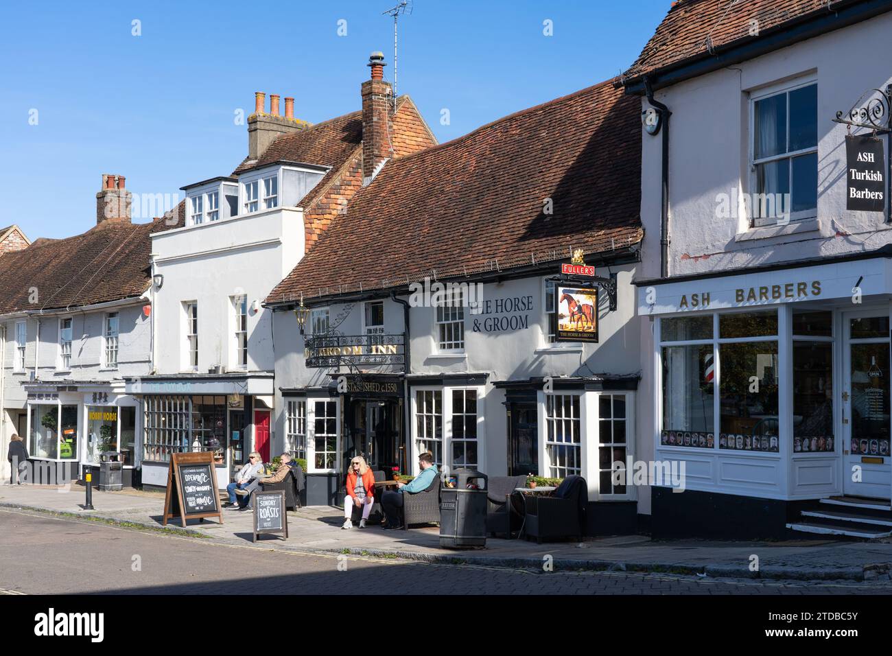 Persone sedute all'aperto al sole al The Horse and Groom, un pub e ristorante in stile rustico con birre chiare chiare su Broad Street a New Alresford, Regno Unito Foto Stock