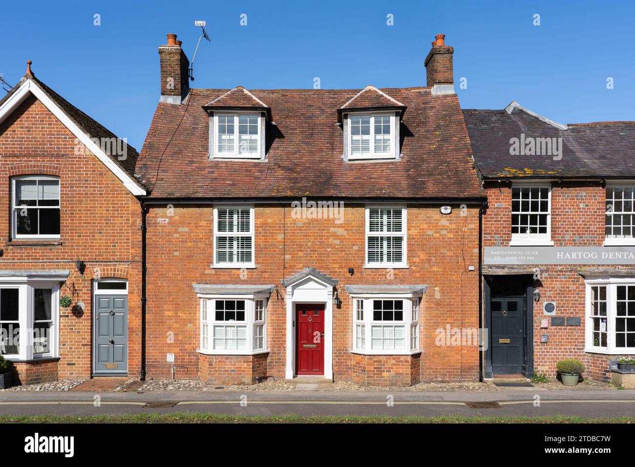 Tipica casa cittadina inglese in mattoni georgiani con un portico georgiano bianco di tipo aperto e una porta d'ingresso rossa. New Alresford, Inghilterra Foto Stock
