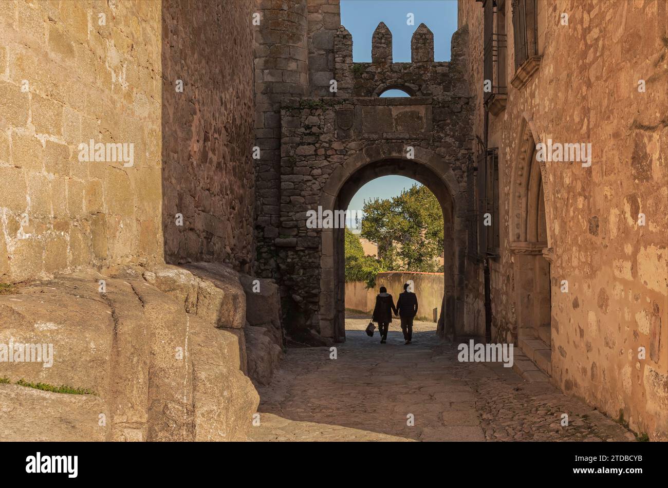 Coppia che cammina giù per la collina tenendosi per mano in un villaggio spagnolo in una giornata di sole Foto Stock