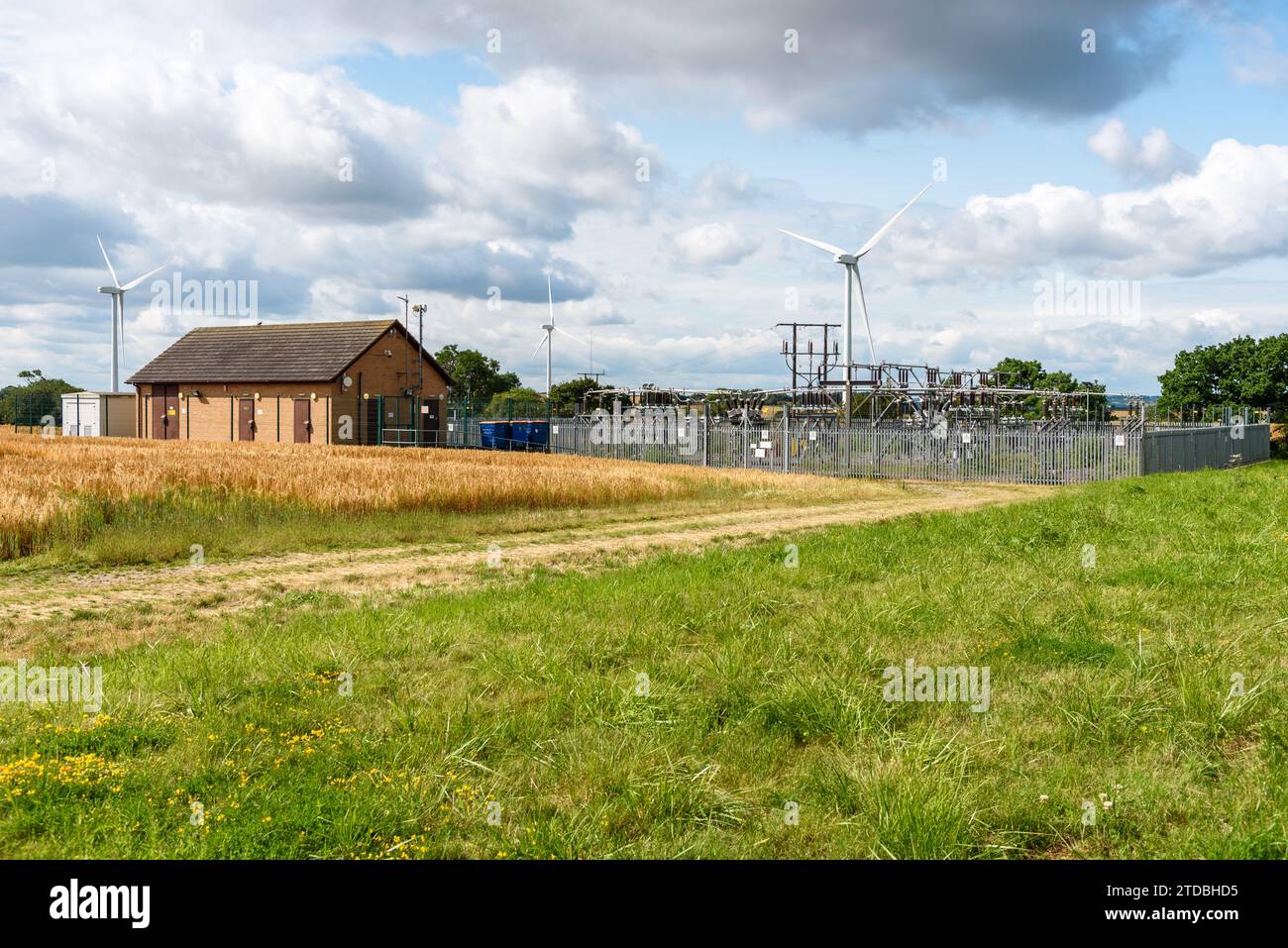Sottostazione elettrica con un parco eolico sullo sfondo nella campagna inglese in una soleggiata giornata estiva Foto Stock