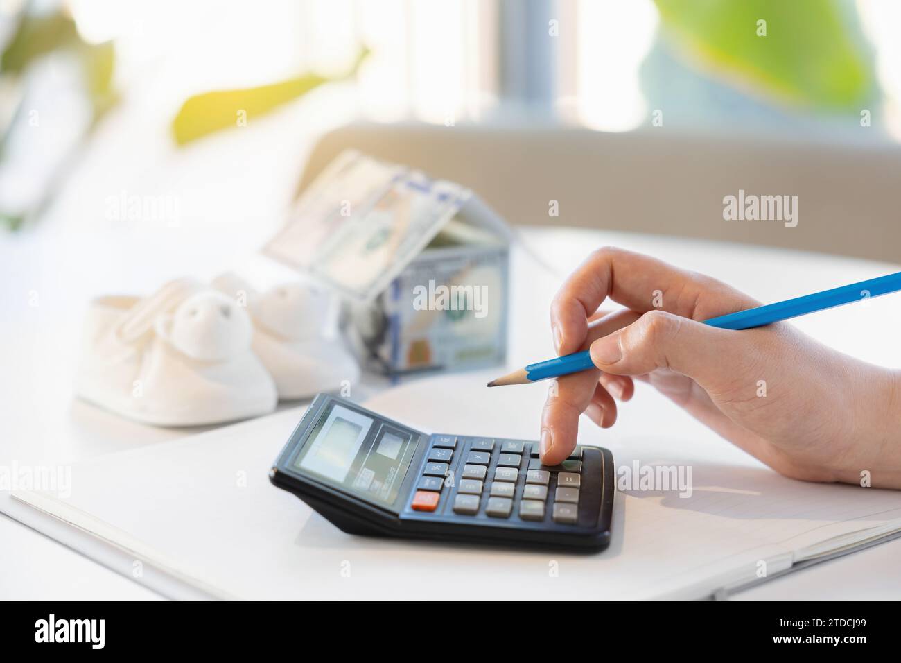 Una donna che si prepara a partorire sta toccando una calcolatrice mentre pensa di comprare una casa Foto Stock