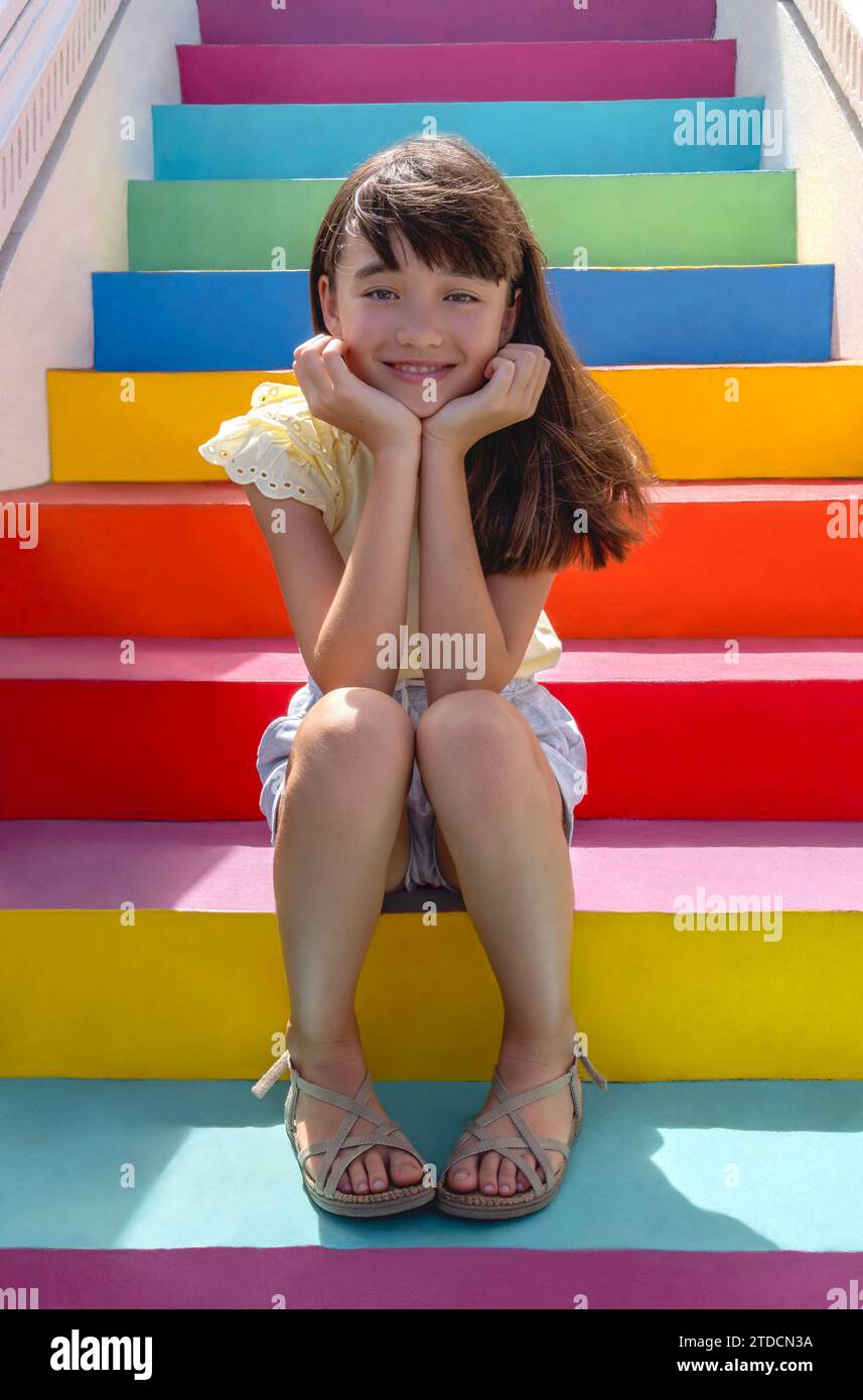 Ragazza di undici anni seduta su scale colorate Foto Stock
