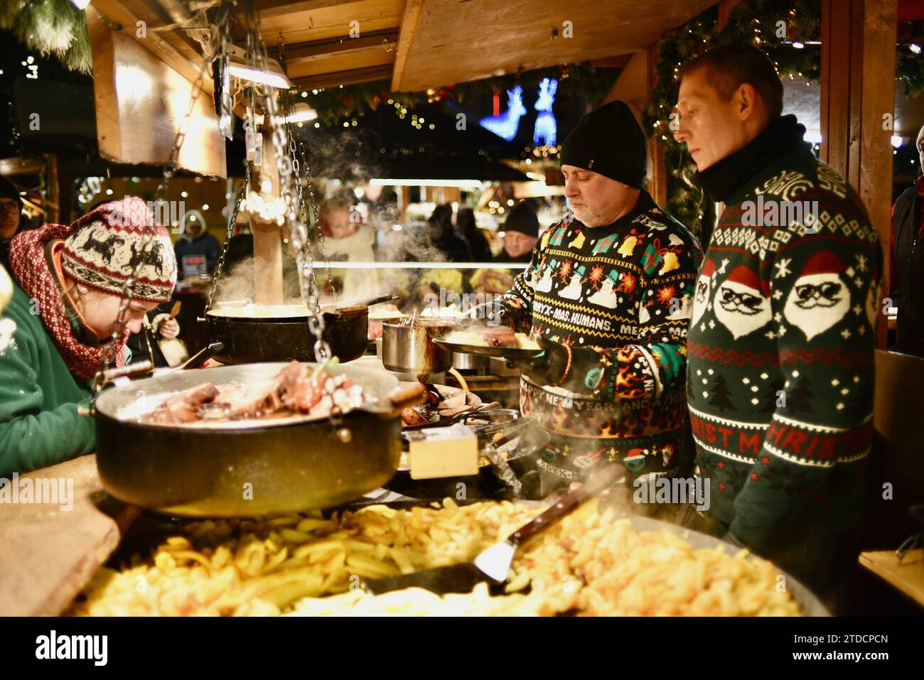 Cuochi che preparano salsicce e altri articoli in bancarelle di cibo all'aperto presso il mercato di Natale di Tallinn nel centro storico medievale di Tallinn, Estonia Foto Stock