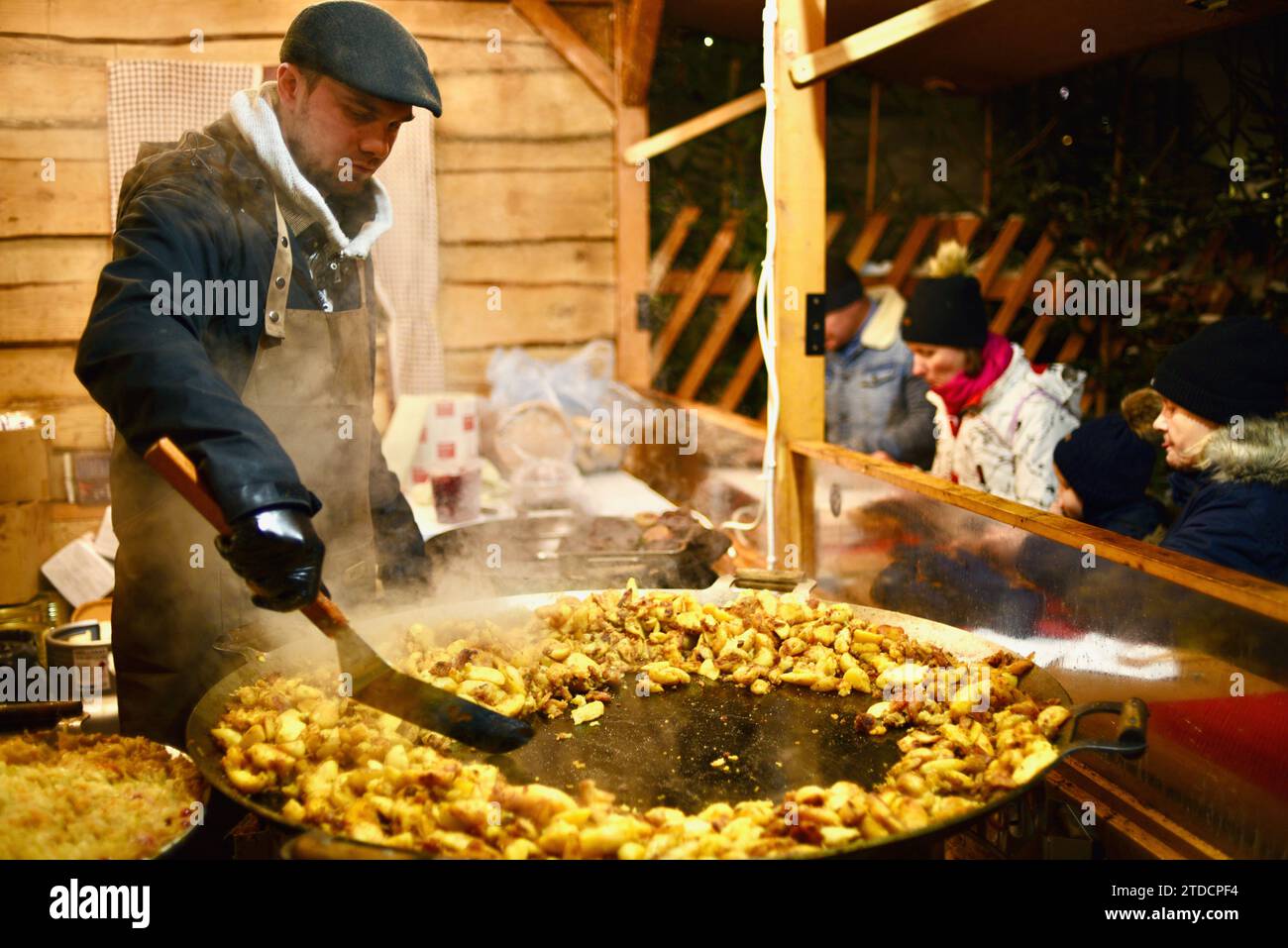 Cuochi che preparano salsicce e altri articoli in bancarelle di cibo all'aperto presso il mercato di Natale di Tallinn nel centro storico medievale di Tallinn, Estonia Foto Stock