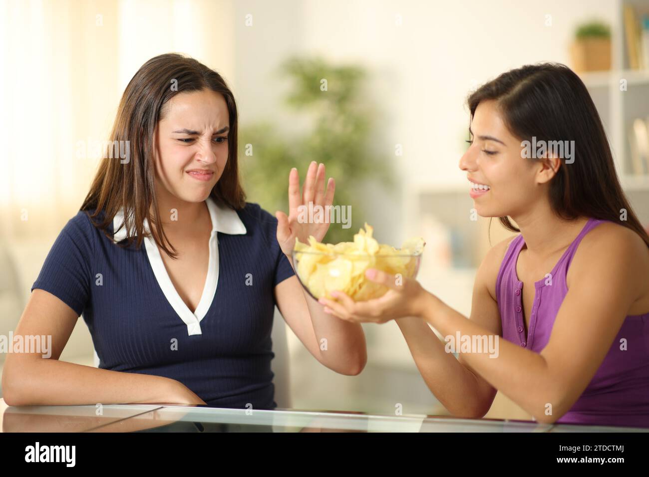 Donna che offre patatine a un amico che lo rifiuta a casa Foto Stock