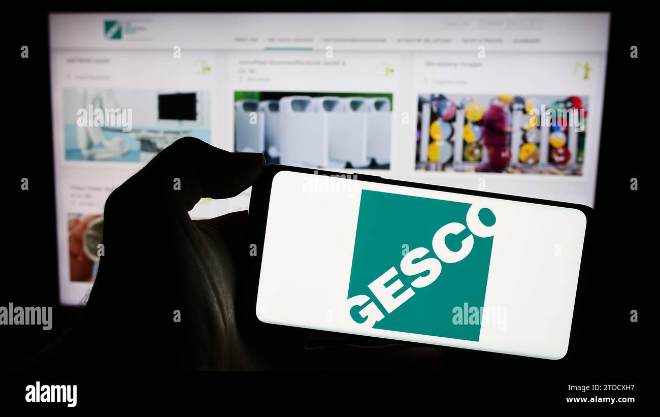 Persona che possiede un telefono cellulare con il logo della società tedesca di ingegneria di processo GESCO se davanti alla pagina Web aziendale. Concentrarsi sul display del telefono. Foto Stock