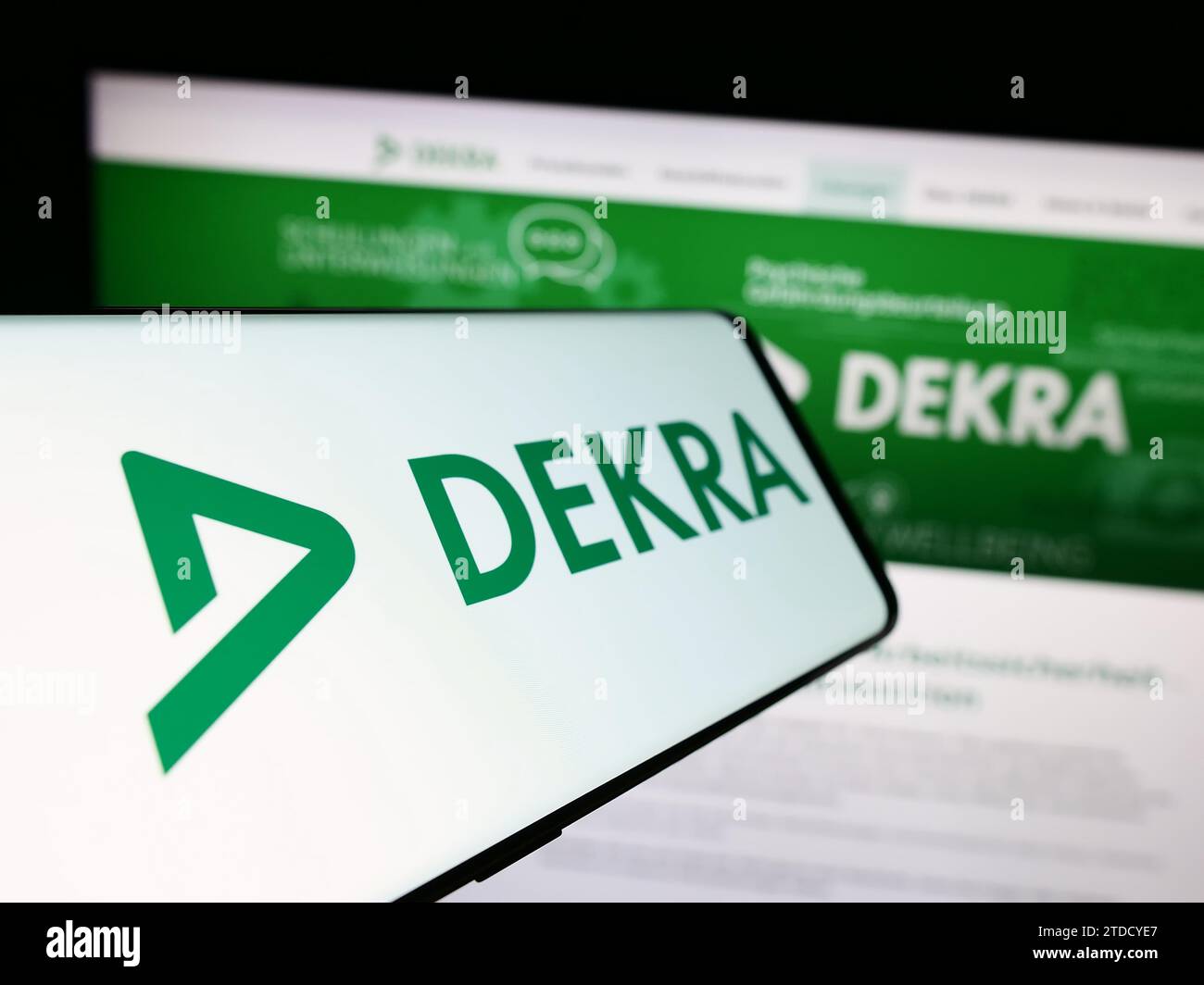 Smartphone con logo dell'organizzazione tedesca di esperti DEKRA davanti al sito Web dell'azienda. Mettere a fuoco il display centrale sinistro del telefono. Foto Stock