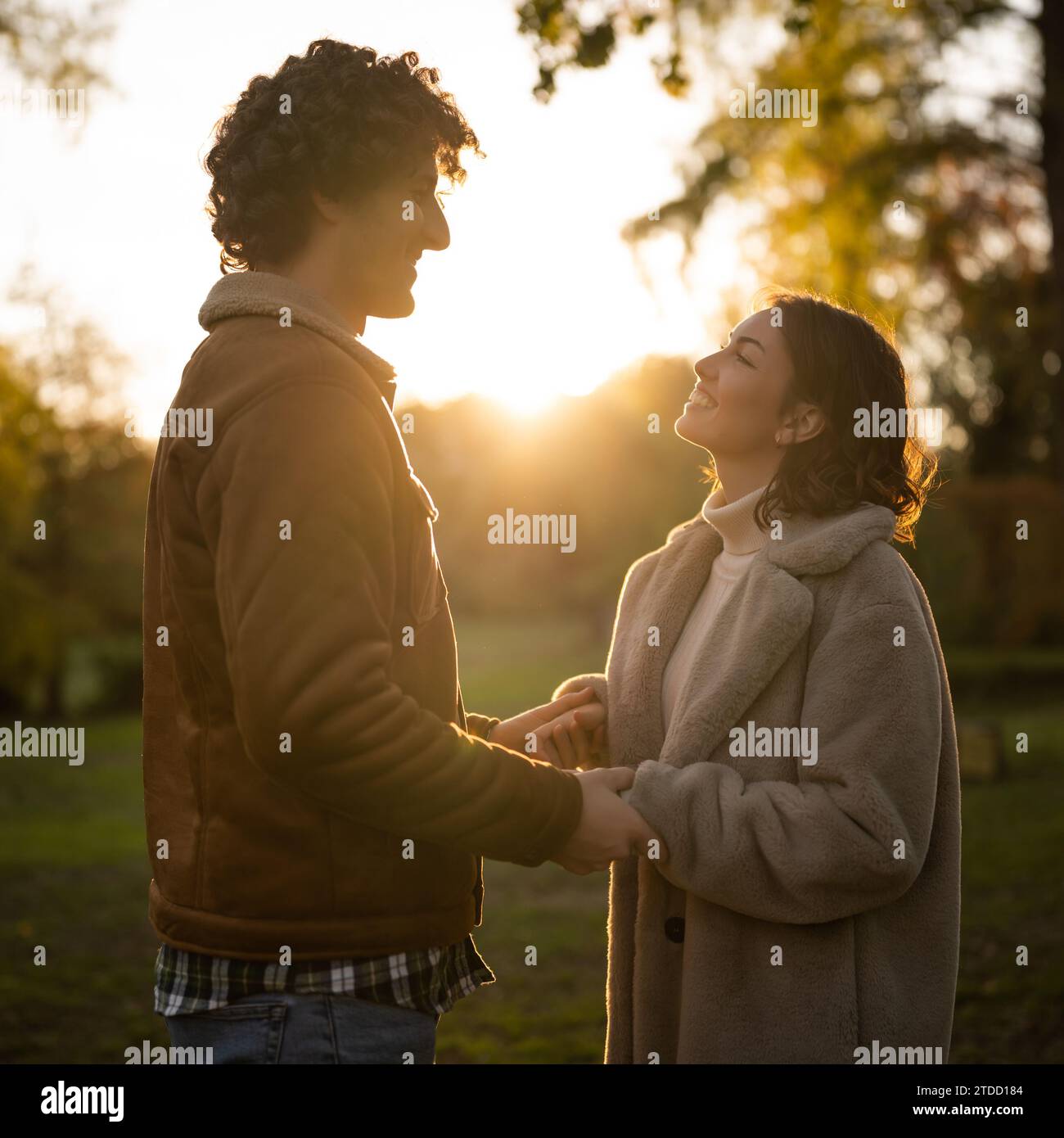 Ritratto di una coppia felice e amorevole al tramonto nel parco. Coppia in silhouette che si guardano. Foto Stock