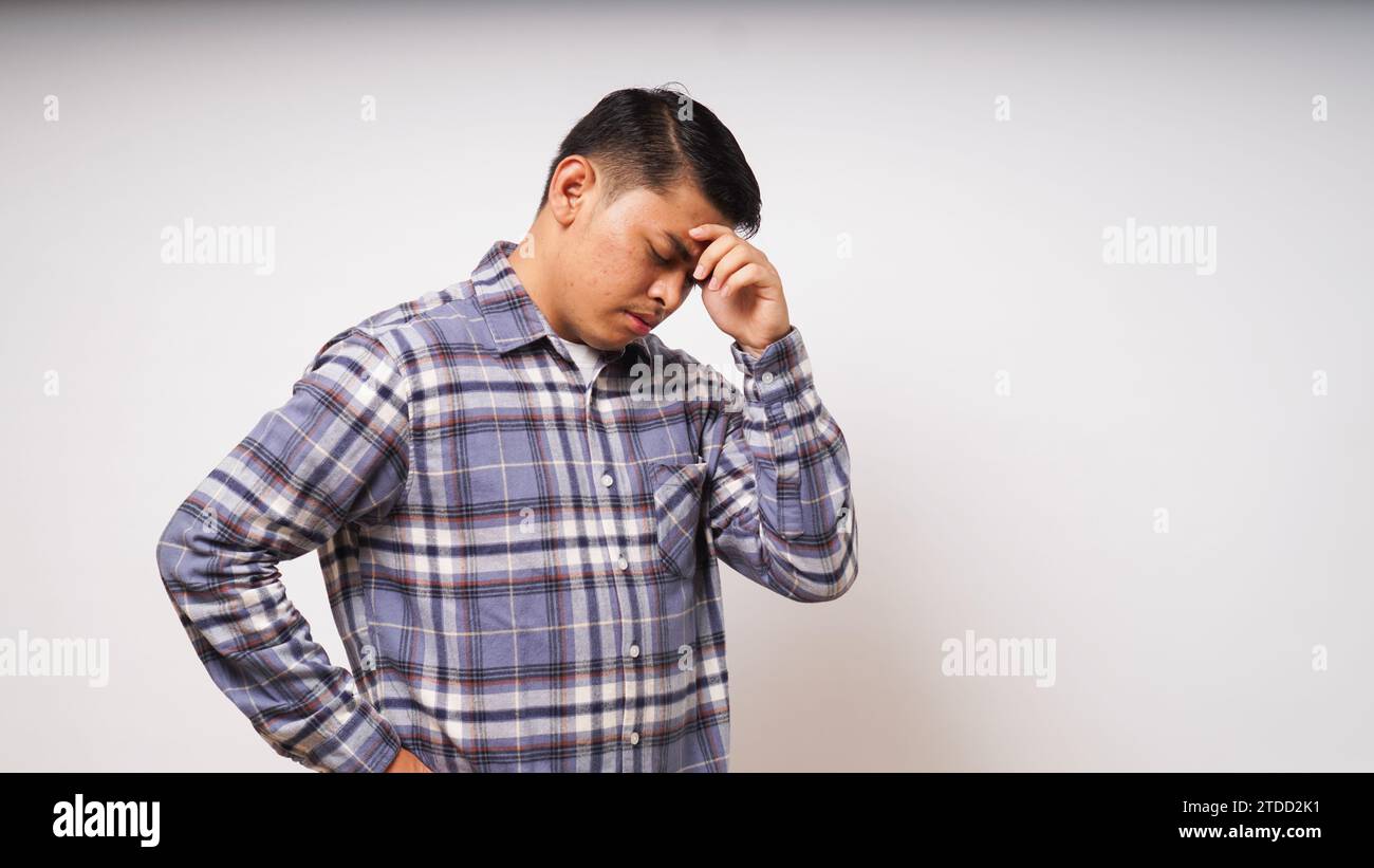 Giovane asiatico che mostra nell'espressione del dolore mentre si tocca la testa Foto Stock