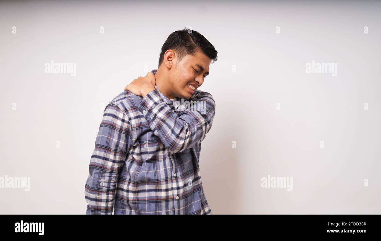 Gesto di un giovane asiatico che soffre di mal di schiena su sfondo bianco, ripresa in studio Foto Stock