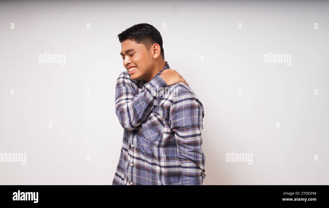 Gesto di un giovane asiatico che soffre di mal di schiena su sfondo bianco, ripresa in studio Foto Stock
