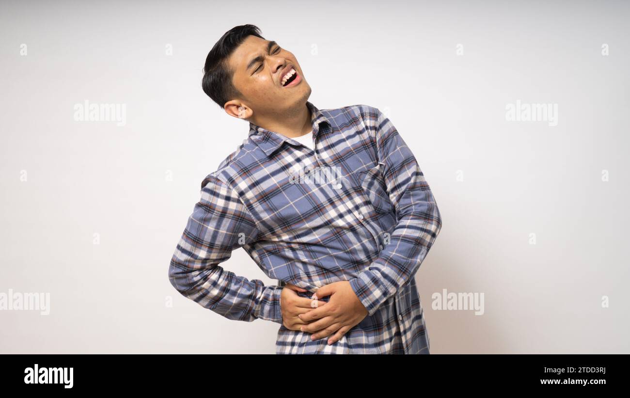 Giovane uomo asiatico che indossa la camicia soffre di mal di schiena basso su sfondo bianco Foto Stock