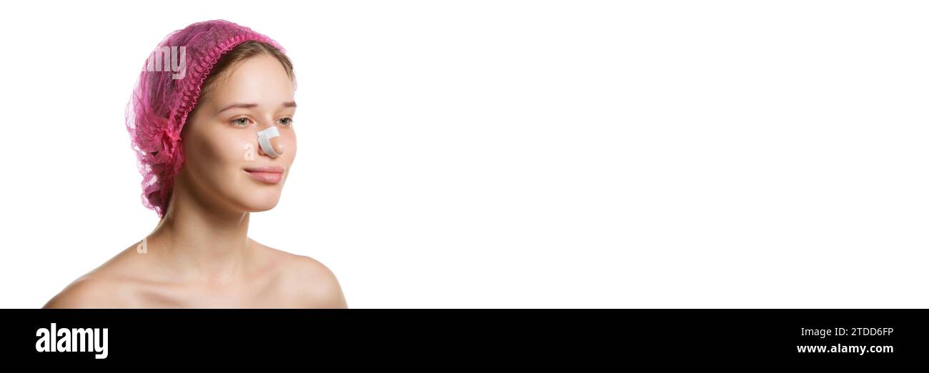 Banner. Ritratto di una donna attraente in berretto rosa con intonaci sul naso dopo rinoplastica su sfondo bianco dello studio con spazio per la copia. Foto Stock