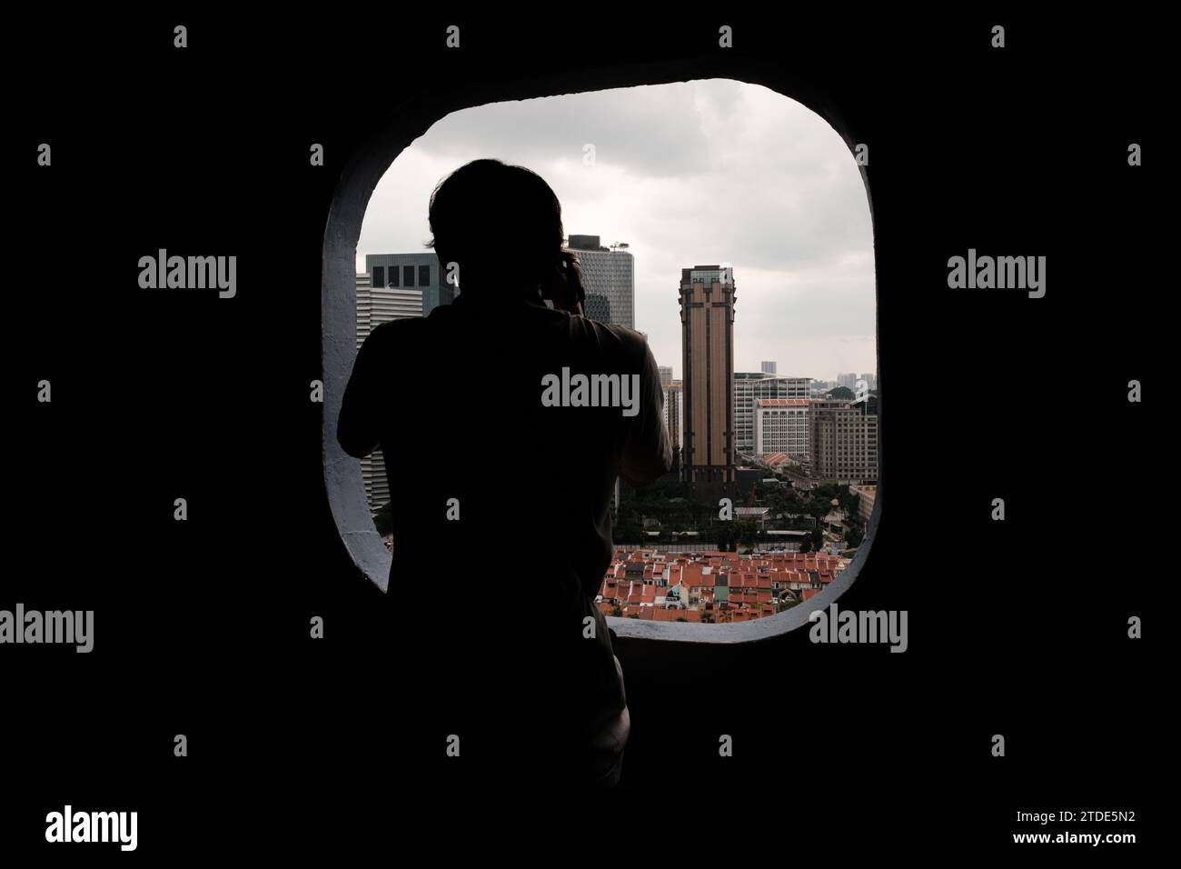 Il giovane fotografo incornicia la città attraverso la finestra Foto Stock