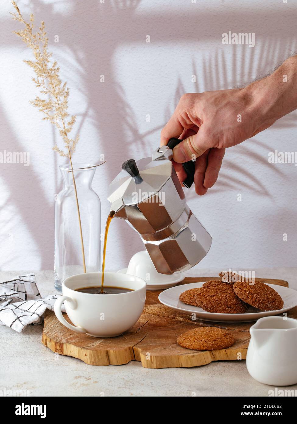 la mano di un uomo versa il caffè in una tazza bianca Foto Stock