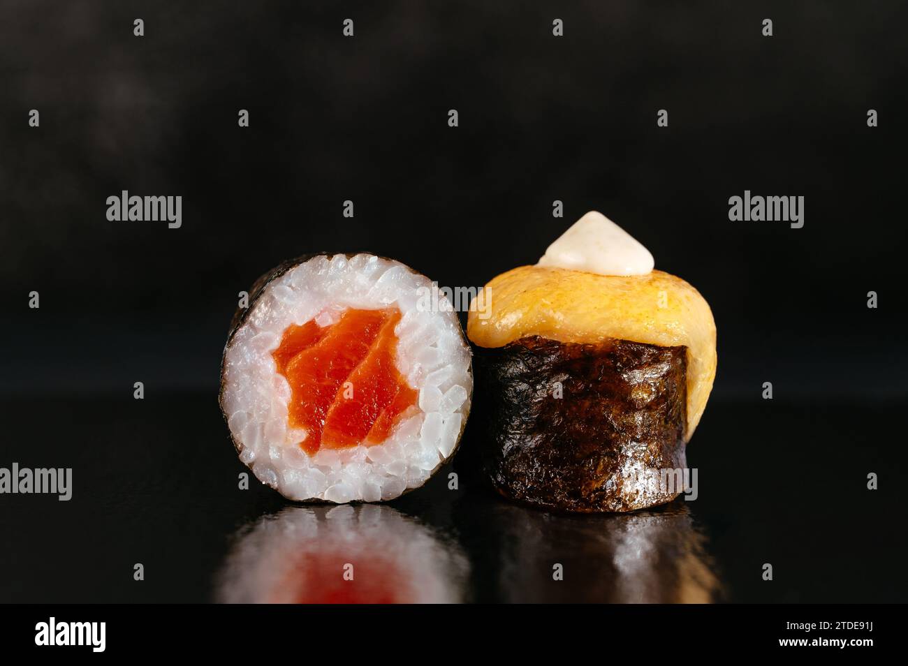 Involtini di sushi giapponesi con un tappo di formaggio su sfondo scuro con Foto Stock