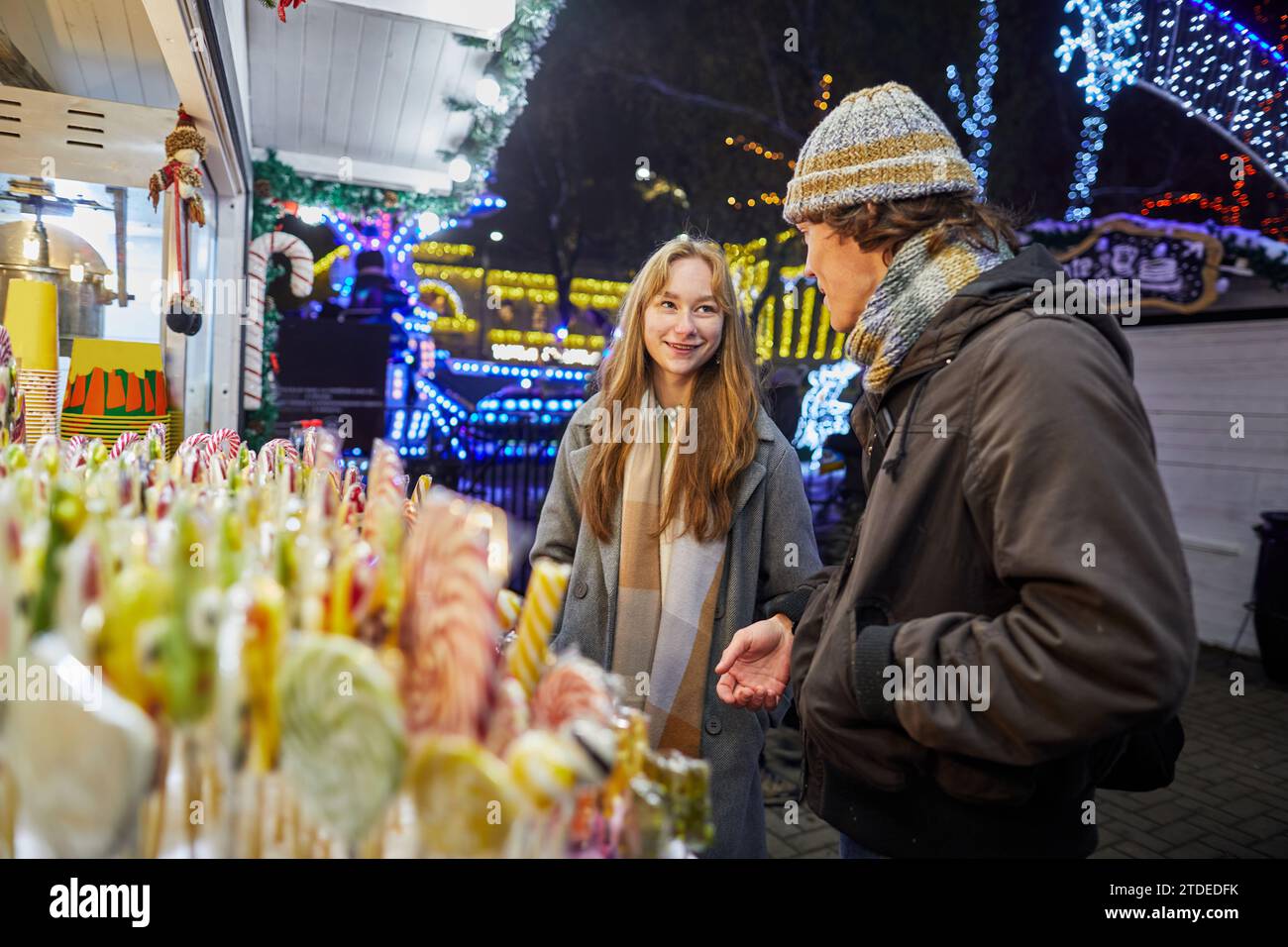 giovane ragazza e uomo che comprano canna da zucchero al mercatino di natale Foto Stock