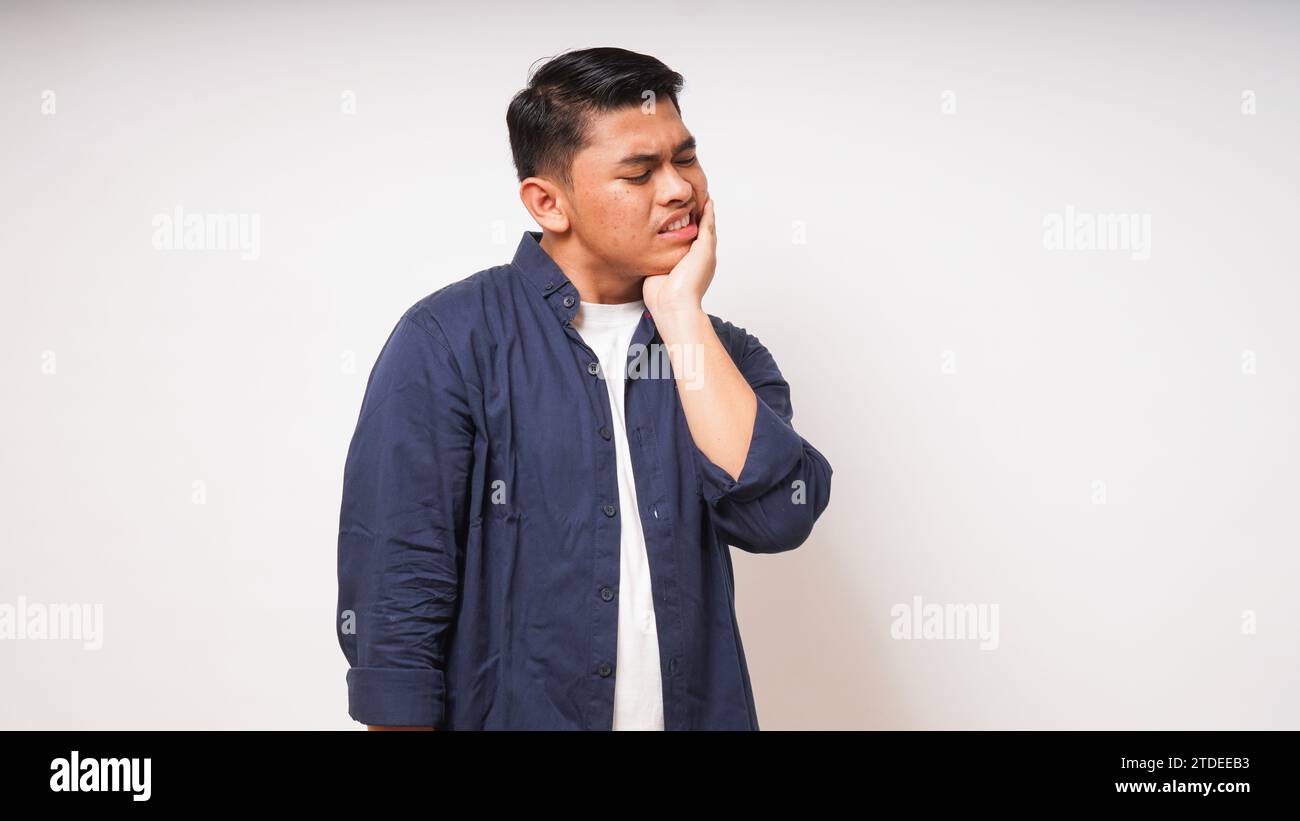 Concetto di mal di denti. Uomo asiatico che tocca la mascella con l'espressione del dolore su sfondo bianco. foto studio Foto Stock