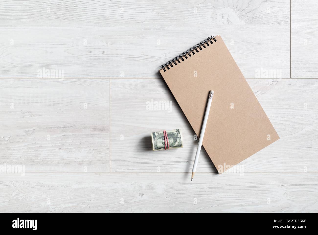 Quaderno vuoto, matita e denaro su sfondo di legno. Copia spazio. Spianatura piatta. Foto Stock